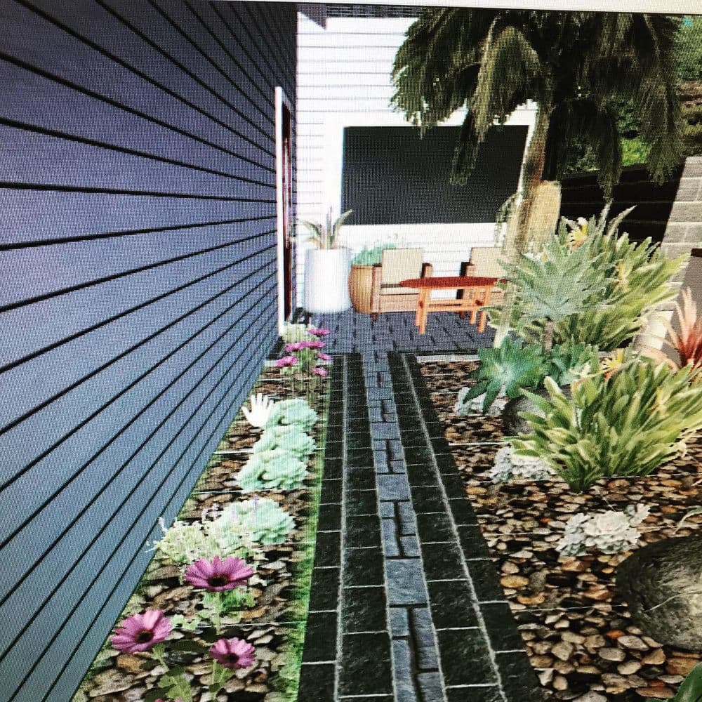 Lush garden path with plants, leading to a cozy seating area by a textured wall.